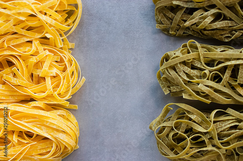 Two types of tagliatelle yellow and green. Egg and spinach noodles on a gray background. photo