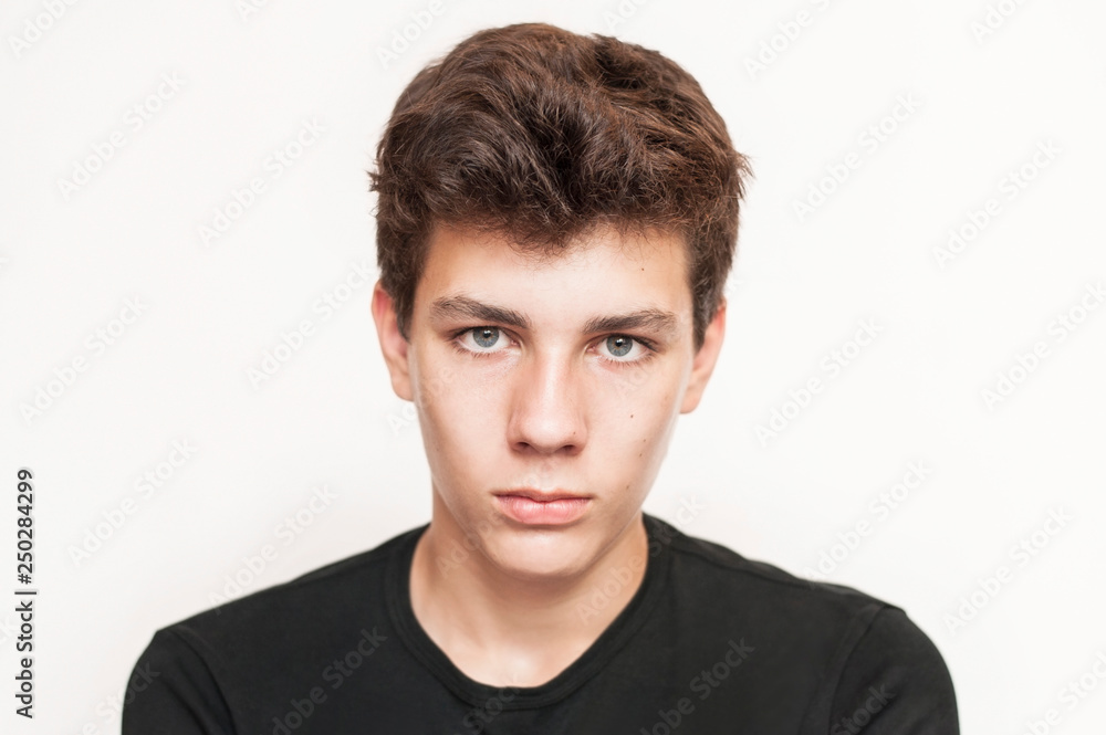 Handsome boy of adolescence with a sad, concentrated face on a light background Handsome boy of adolescence with a sad, concentrated face on a light background