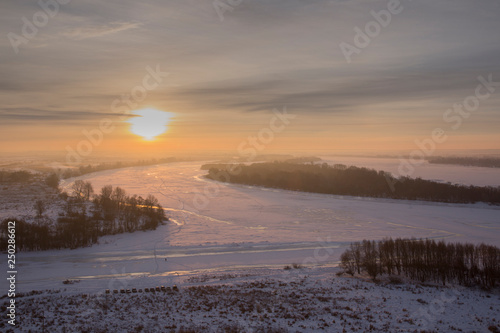 Panoramic view on frozen river and forest on hill in winter during sunset from hill © salman2