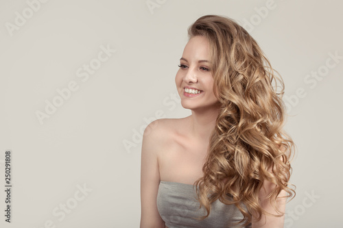 woman on a gray background with wavy blond hair. happy smile. The concept of clean skin. copycpase