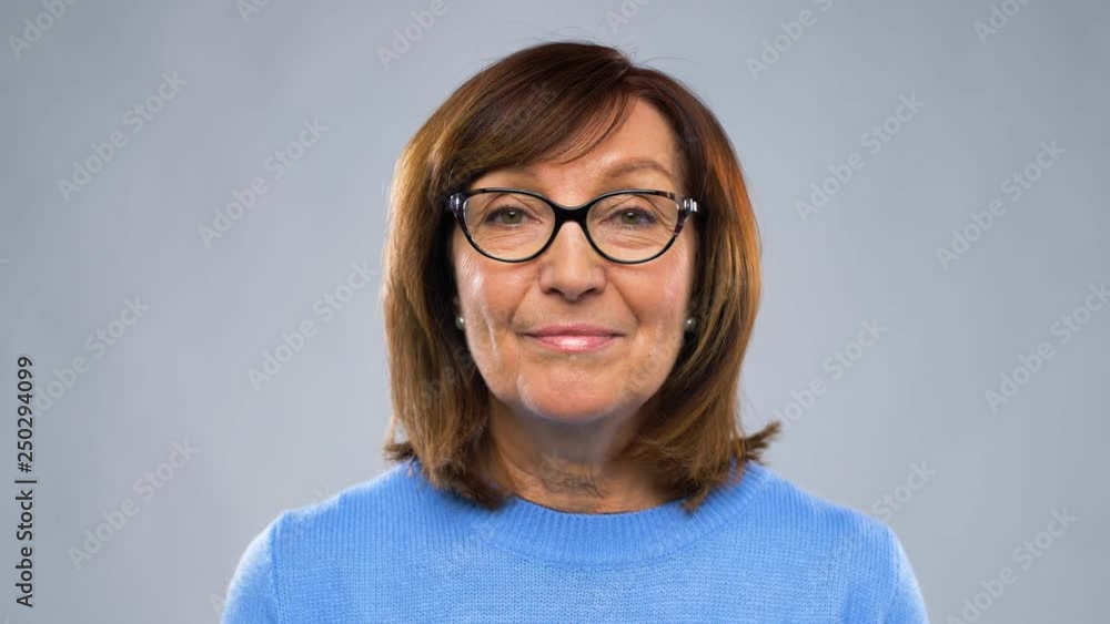 communication, age and people concept - happy senior woman in glasses having video chat or interview over grey background
