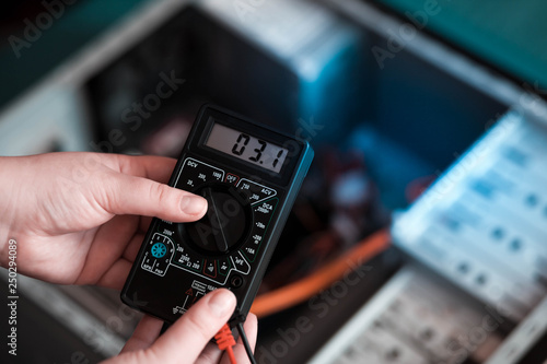 Computers repair concept. Electronics service technician measures voltage with a voltmeter. Voltage tester in the hands of a specialist