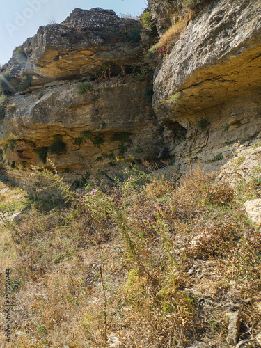 Bottom view on the steep cliff of Tarki-tau mountain. Grass on the eastern slope turned yellow from the heat
