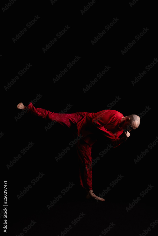 Male in red costume practicing qigong in the dark