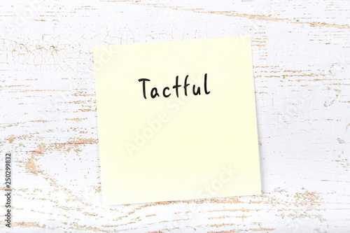 Yellow sticky note with handwritten word tactful