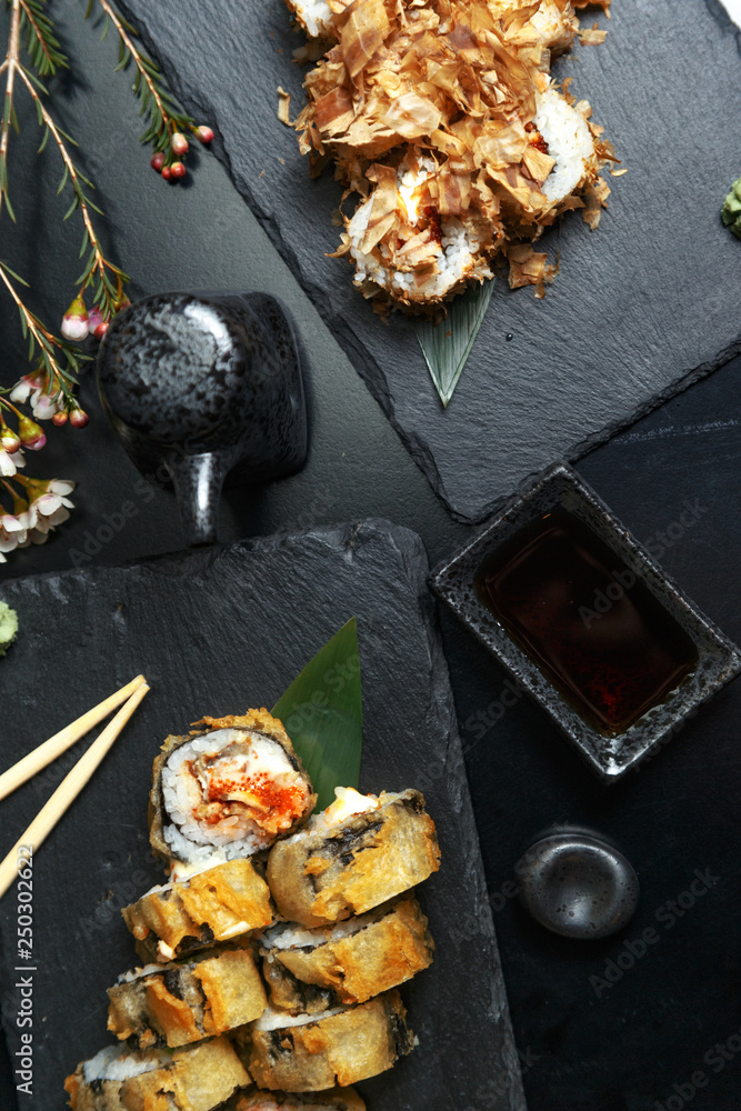 Fresh sushi rolls on black slate. Restaurant table setting. Fresh sushi rolls on black slate. Restaurant table setting.