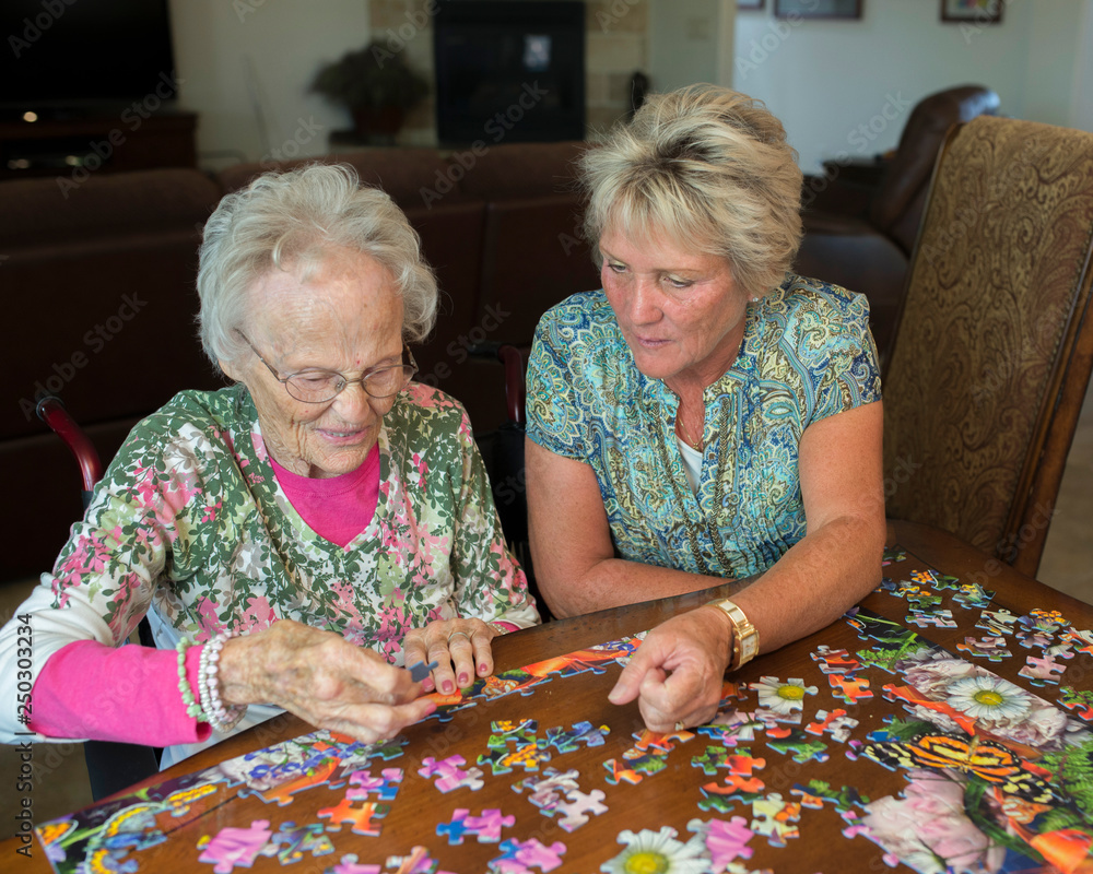Daughter helps elderly mother put together puzzle Daughter helps elderly mother put together puzzle