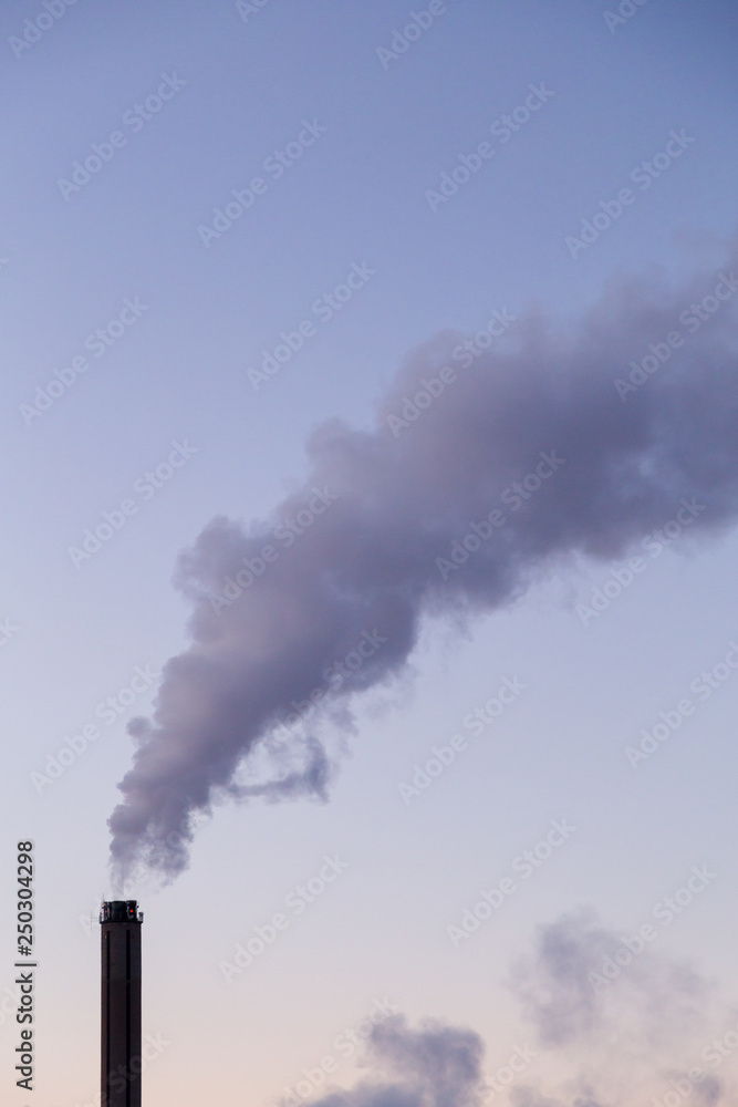 Smoke coming from a heat plant chimney on a cold winter evening