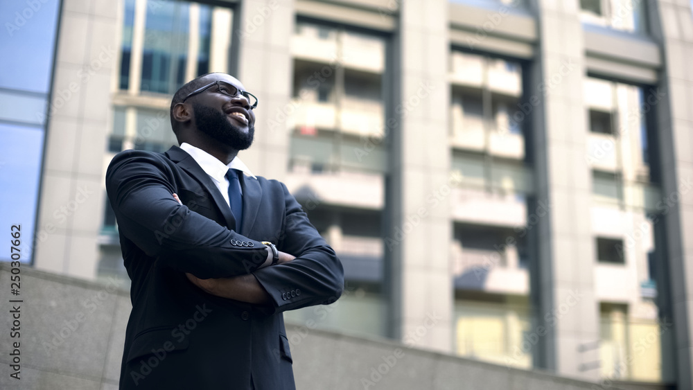 Afro-american man in suit looks up into bright future, motivated for success