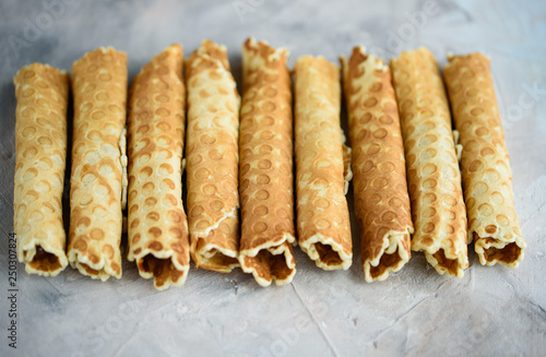 Waffle rolls, tasty and fragrant, with boiled condensed milk on a concrete background