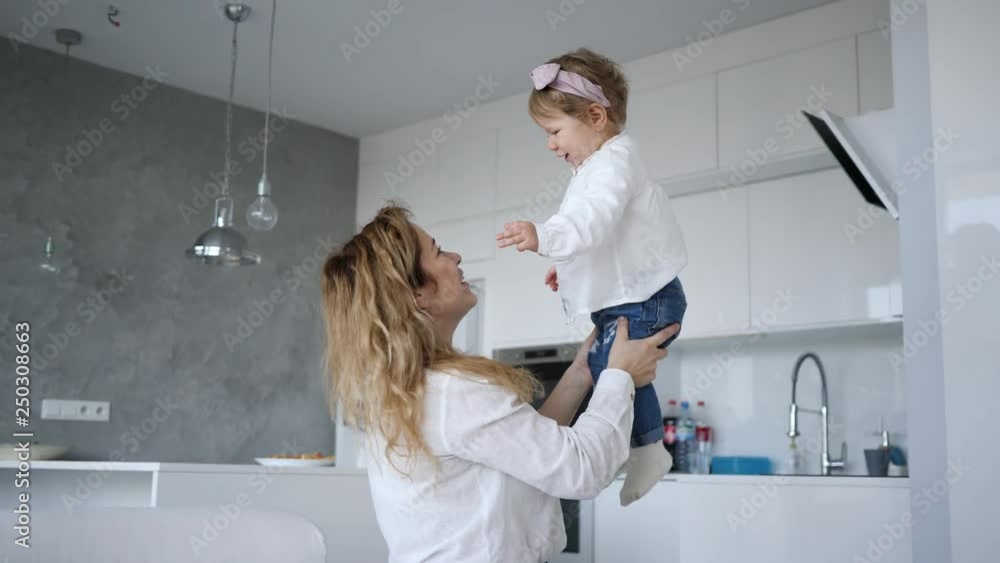 Joyful mother funny playing with her cute little baby girl daughter at home