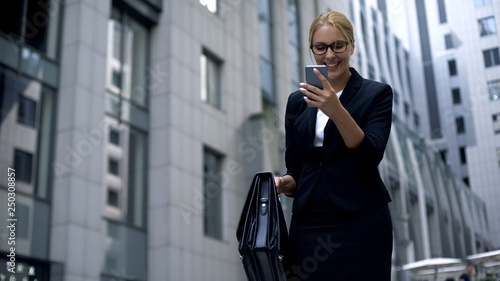 Business lady excited about good news from phone, successful deal, promotion