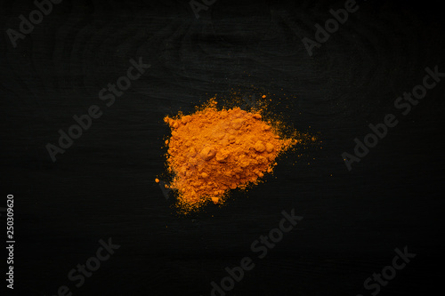 Close-up image of turmeric, curcuma powder on black wood background, view above