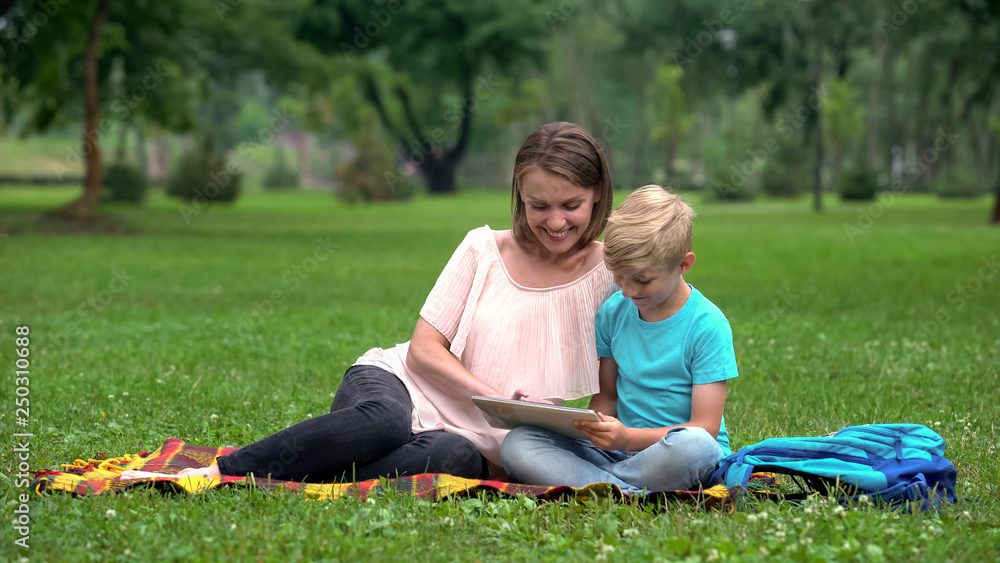 Mother and son using tablet computer in park, wireless internet access anyplace Mother and son using tablet computer in park, wireless internet access anyplace