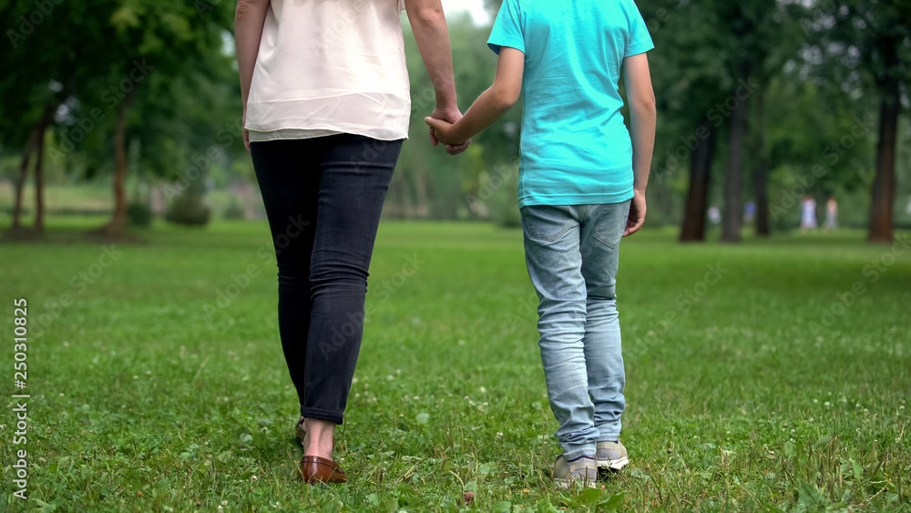 Mother and son holding hands, walking away together, concept of child adoption Mother and son holding hands, walking away together, concept of child adoption