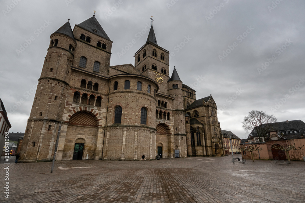 Trier / Germany - February 9 / 2019 : front view of Saint Peter's cathedral at a cloudy day and a tree at side of it