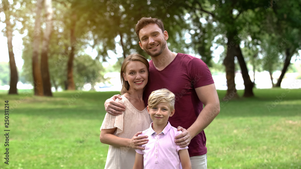 Naklejka premium Happy family embracing and looking at camera, social insurance, protection