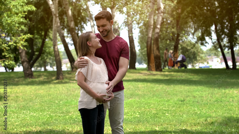 Pregnant family posing on camera in park, happy maternity and prenatal care Pregnant family posing on camera in park, happy maternity and prenatal care