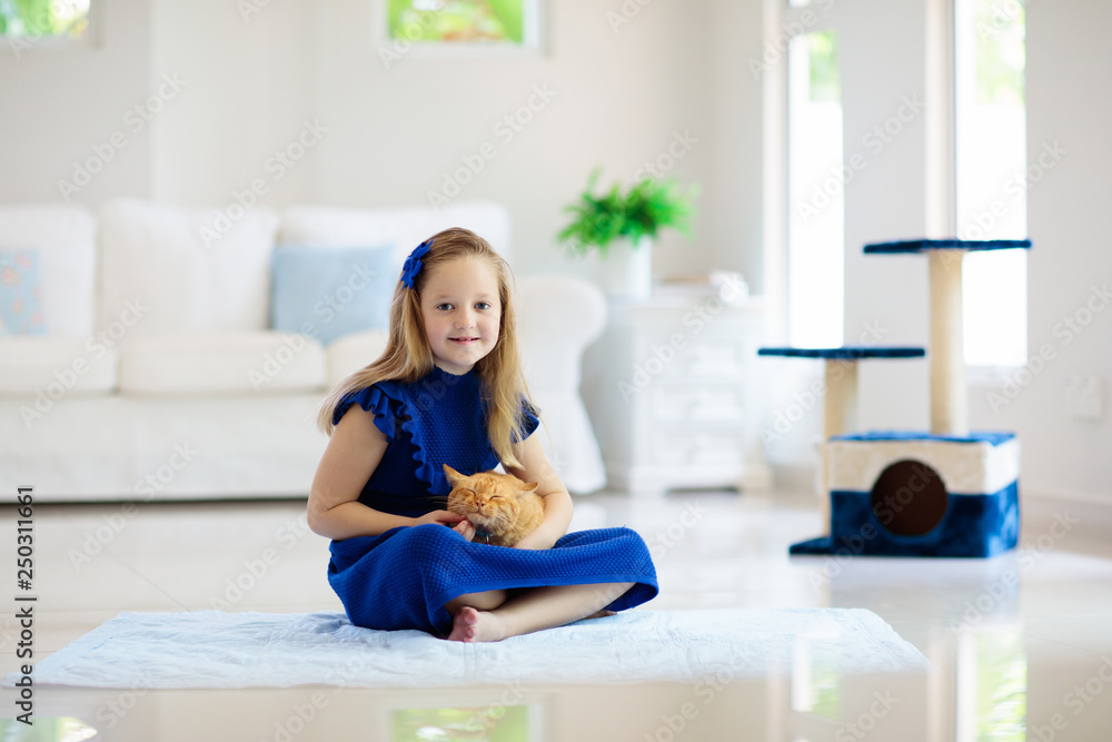 Child playing with cat at home. Kids and pets.