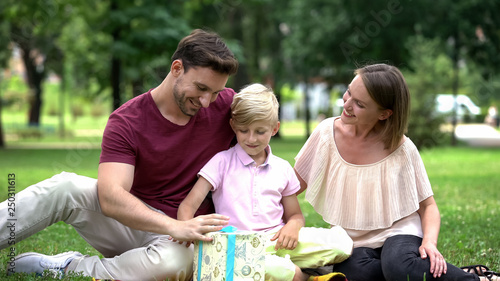 Family giving son gift box, congratulating boy with good marks at school, care