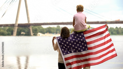 Family wrapped in American flag looking at bridge, immigration for better life photo