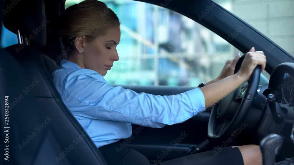 Exhausted woman closing eyes sitting in car, trying to relax after hard work day
