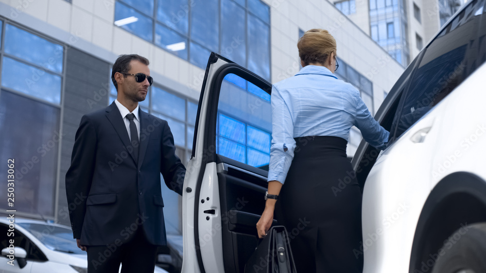 Personal assistant of female politician opening car door to his boss, service Personal assistant of female politician opening car door to his boss, service