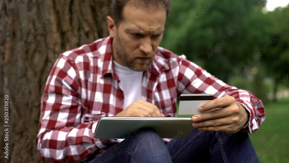 Man entering credit card number on tablet, paying online parking bills and fines Man entering credit card number on tablet, paying online parking bills and fines