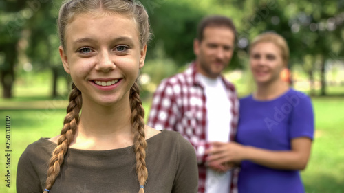 Beautiful teen girl smiling on background of her happy parents, caring family