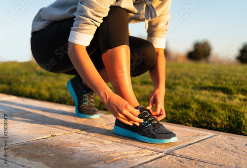 Young woman tying shoelace of sneakers to make outwork training running. Fitness and healthy lifestyle photo