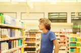 Man shopping in supermarket reading product information.(washing powder,detergent)