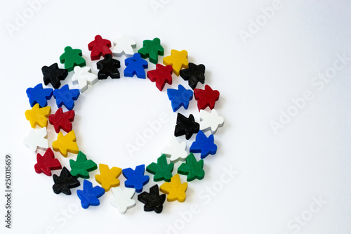 Groups of colorful meeples in circle isolated on gray background. Colorful round frame of game components. Small figures of man. Board games concept. Business strategy. Party time with card games.