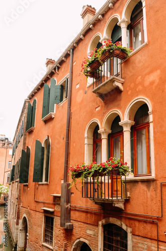 Street view with windows and balconies with flowers and old houses in Venice  Italy.
