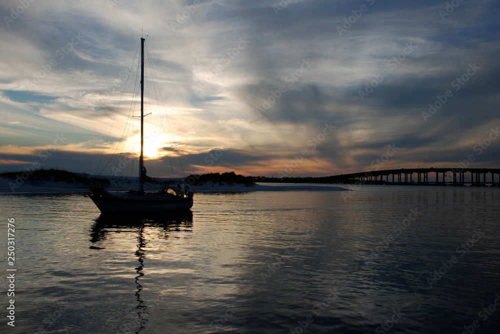 Sailboat at sunset in Destin Florida with bridge in background