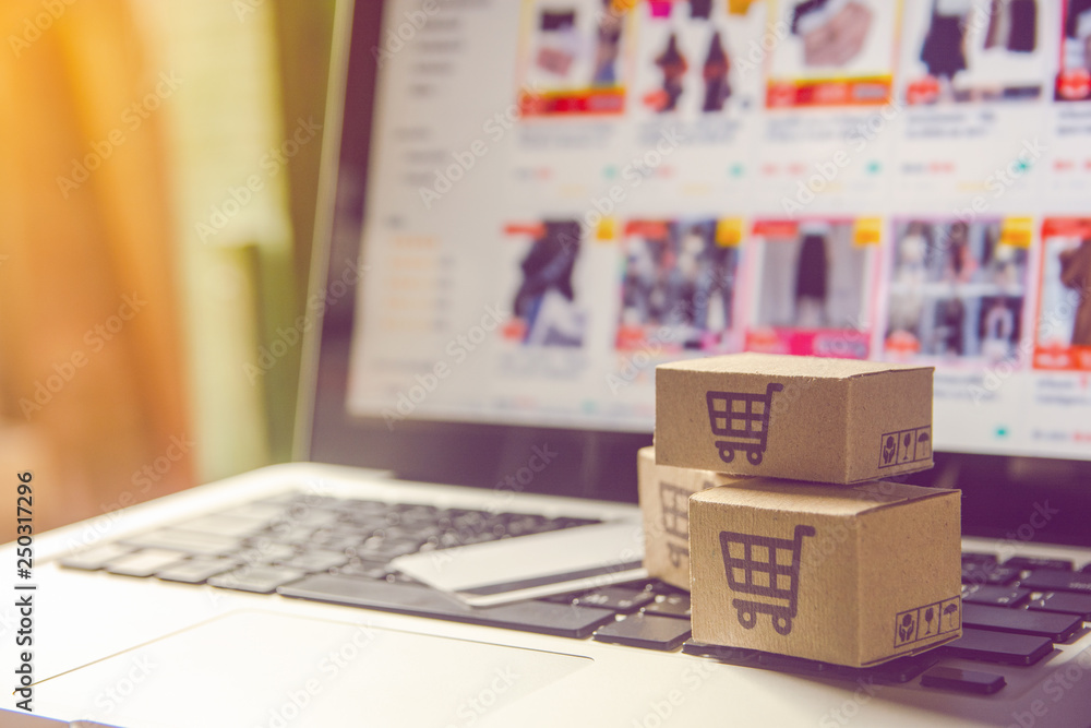 Obraz premium Shopping online concept - Shopping service on The online web. with payment by credit card and offers home delivery. parcel or Paper cartons with a shopping cart logo on a laptop keyboard