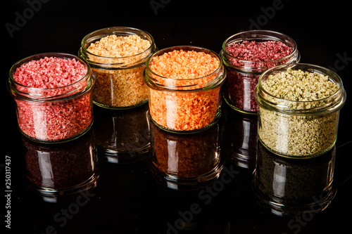 closeup small glass jars filled with different colors sea salt