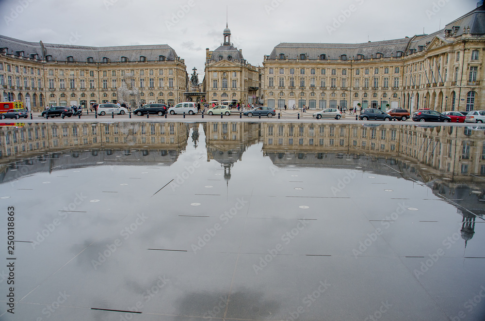 Reflection of neoclassical buildings in the water mirror of the Place de la Bourse de Bordeaux
