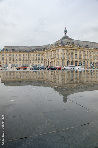 Reflection of neoclassical buildings in the water mirror of the Place de la Bourse de Bordeaux