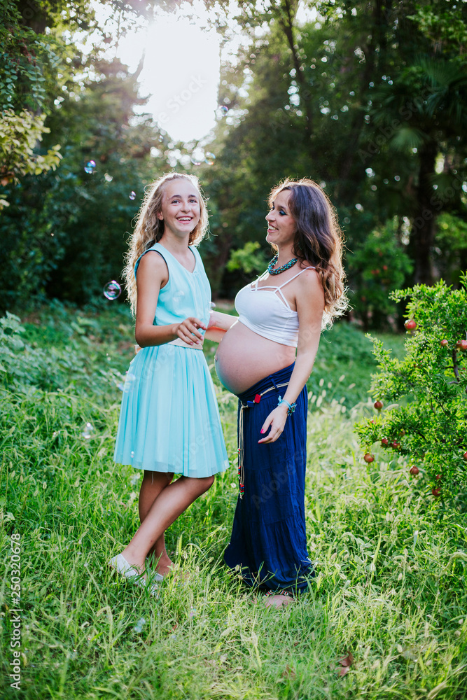 pregnant mother and daughter happy in the field pregnant mother and daughter happy in the field