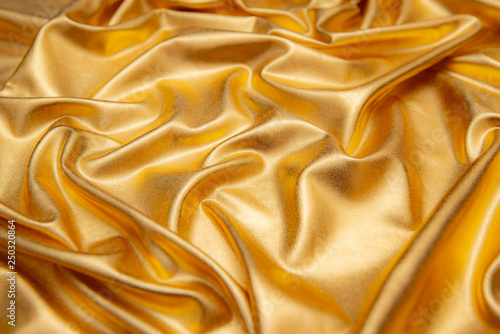 golden abstract background of luxury cloth wave,grunge lame.Texture of sheet crumled.