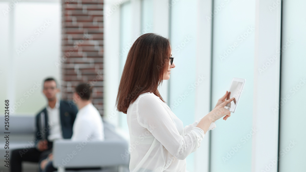 businesswoman with a digital tablet standing near the office window businesswoman with a digital tablet standing near the office window