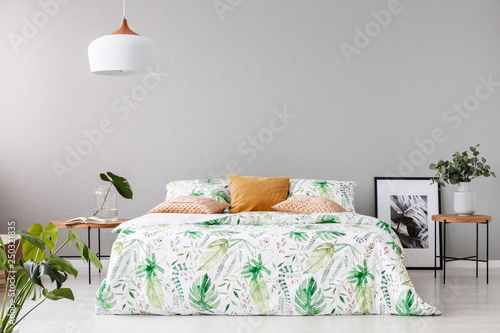 Vászonkép Double bed with floral duvet and peach colored pillow between two wooden nightst