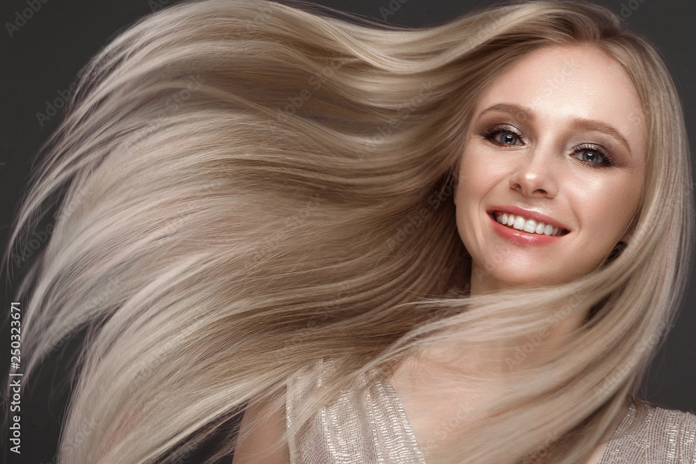 Fototapeta premium Piękna blond dziewczyna w ruchu o idealnie gładkich włosach i klasycznym makijażu. Piękna twarz.