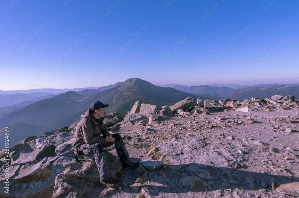 A man on top of a mountain. A man looks into the distance.