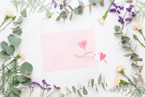 Flowers composition. Paper blank, carnation flowers, eucalyptus branches on pastel background. Flat lay, top view, copy spaceFlat lay stiil life.