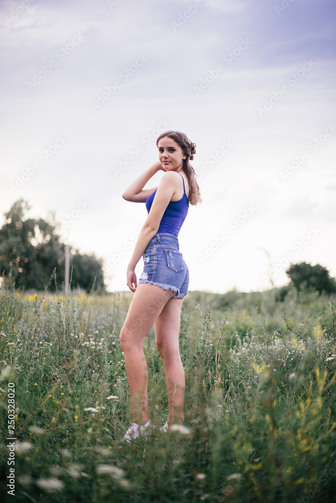 Beautiful girl in short shorts and in a blue T-shirt on the field Beautiful girl in short shorts and in a blue T-shirt on the field