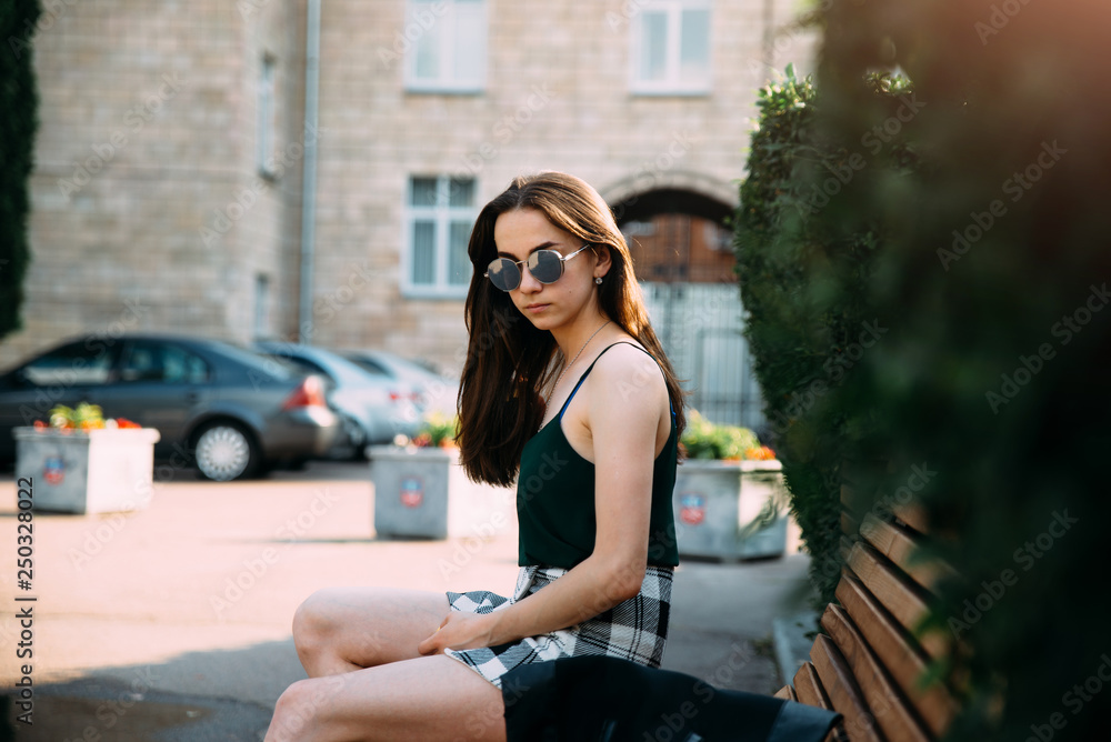 A girl in a black shirt and shorts in a park on a bench