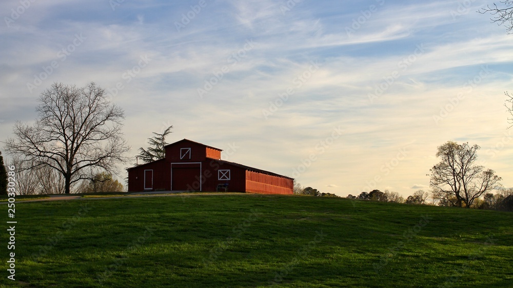 Red barn on a green hill.