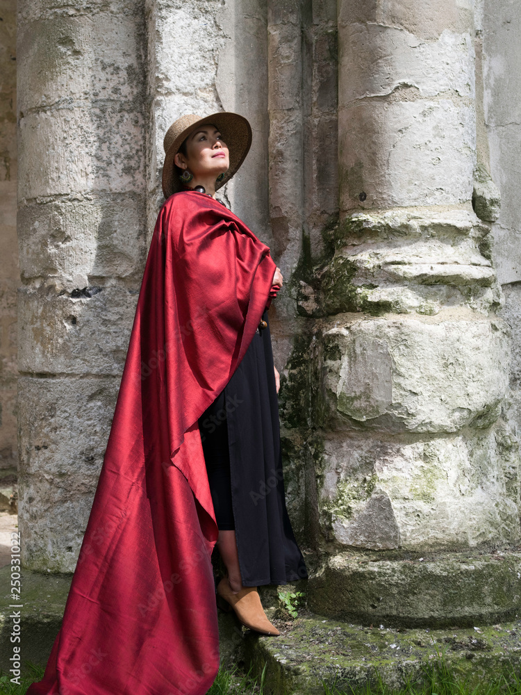 Femme avec une étoffe se doie rouge dans les ruines d'une église du moyen age