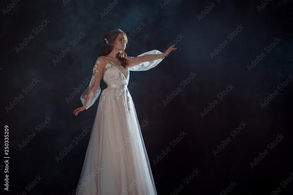 Young beautiful woman in wedding dress with wide light skirt. Dark background, fantasy style